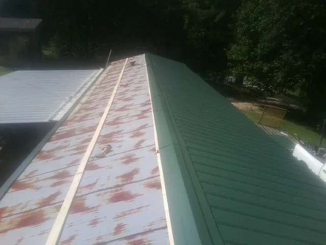 Old rusted panels beside newly installed green metal roofing — Wind Damage Roof Repair by Roofing Brothers in Grizzly Flats