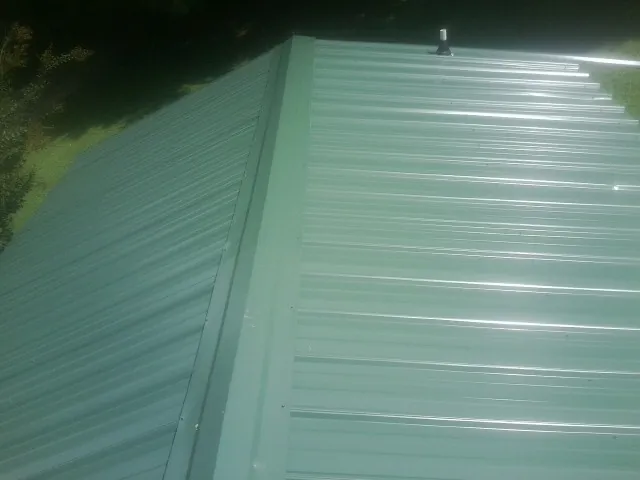 New green metal panels meeting at the ridge of a roof — Flat Roof Repair work by our crew in Grizzly Flats
