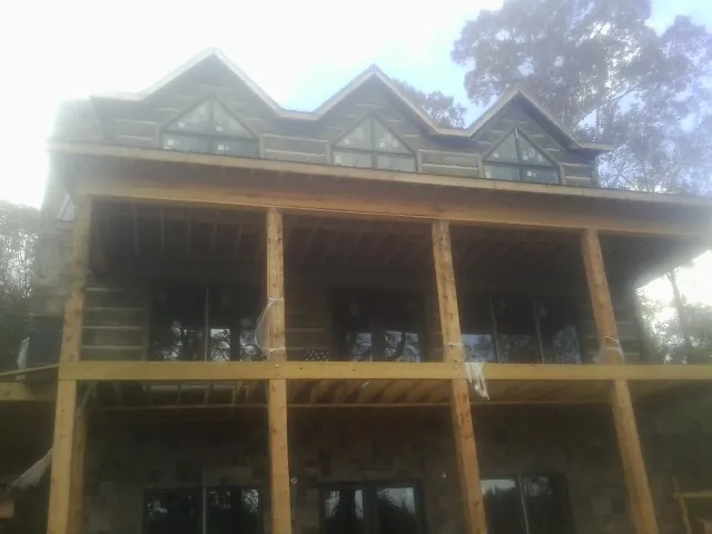 Dormers and porch framing on a large log home under construction — Roof Coating work by our crew in Grizzly Flats