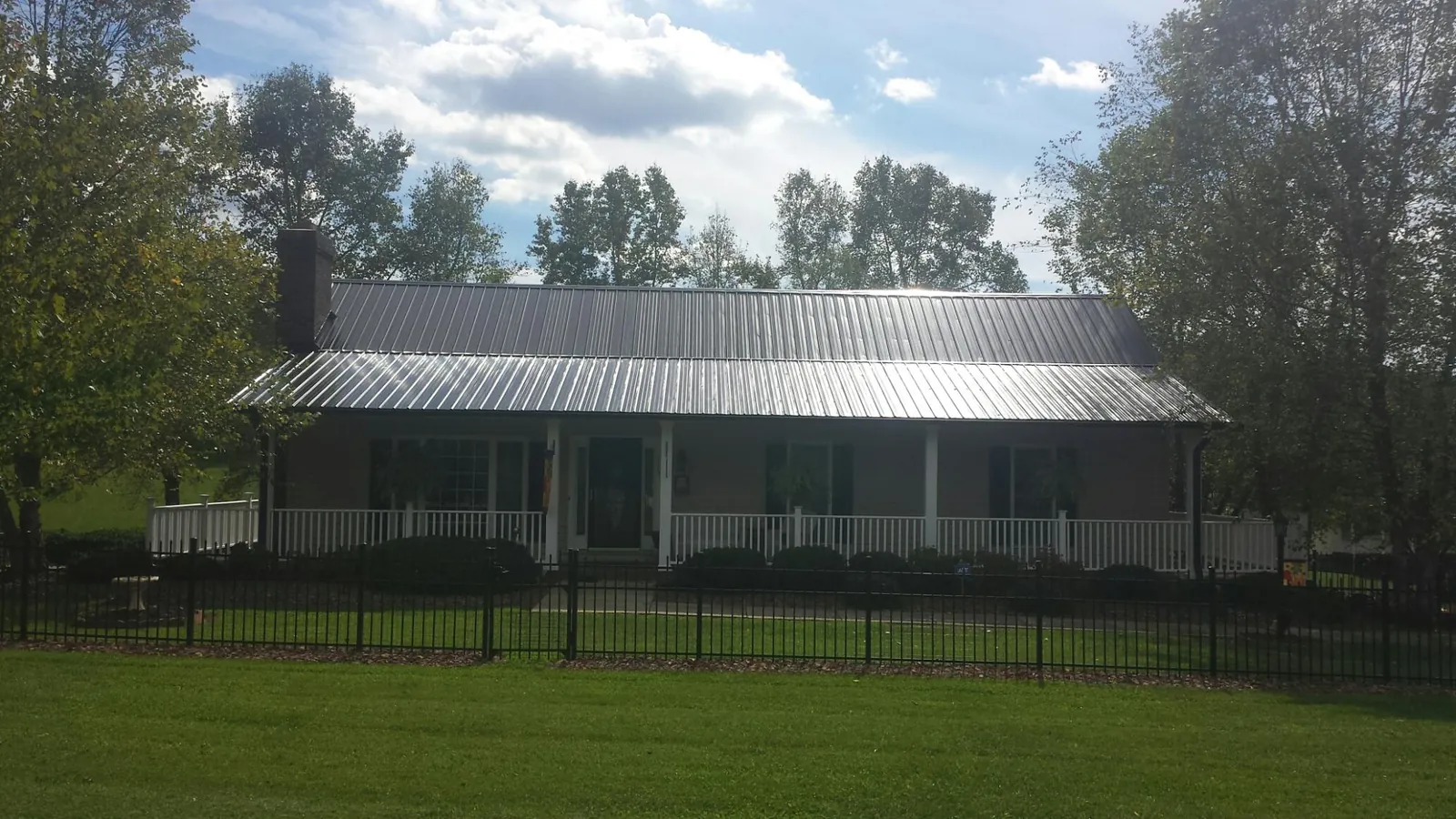 Gray metal roof on a brick ranch with a full width front porch — Gutter Guard Installation work by our crew in Grizzly Flats