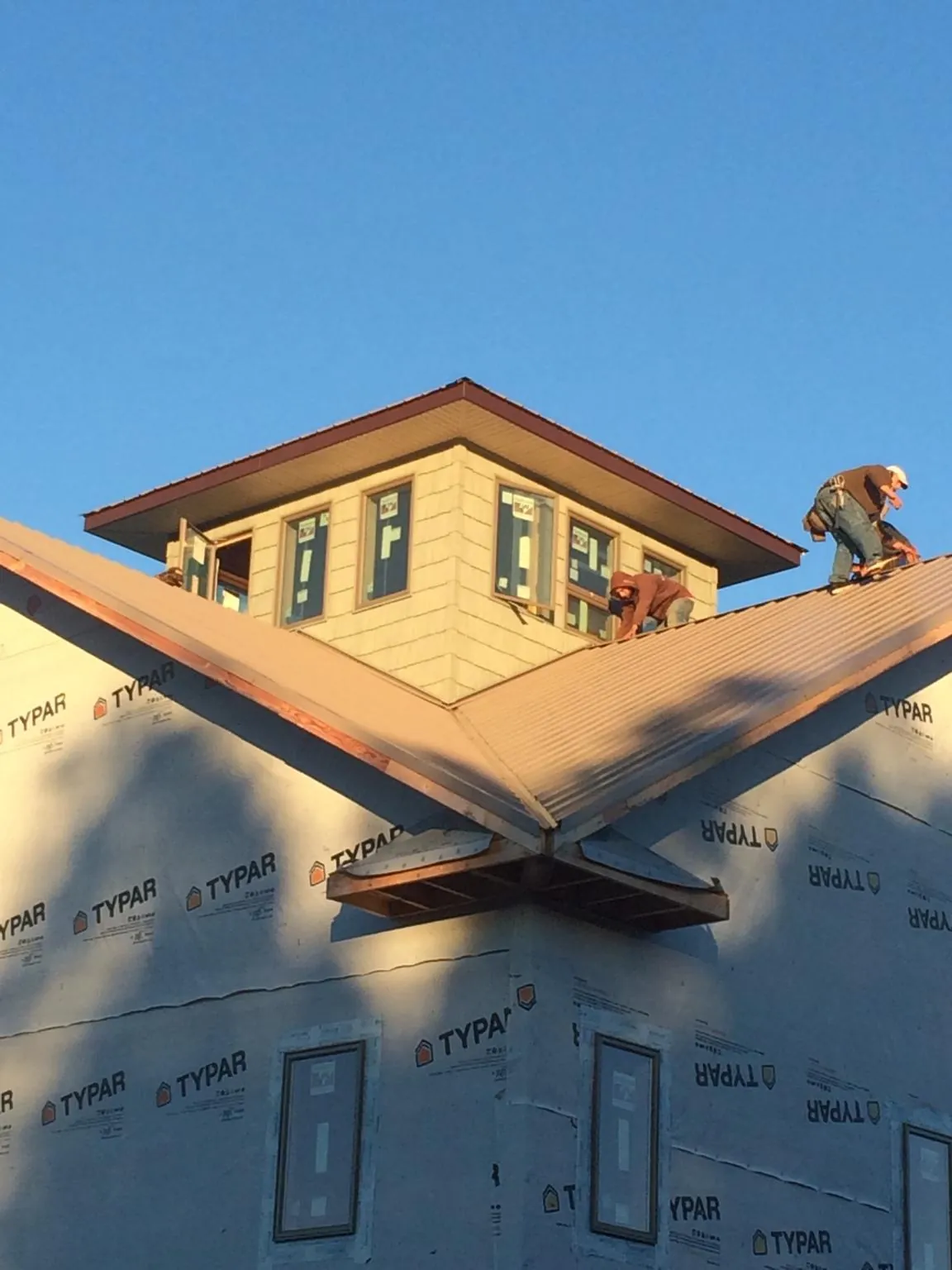 Roofers working around a rooftop cupola on a new metal roof at sunset — Roof Waterproofing in Grizzly Flats by Roofing Brothers